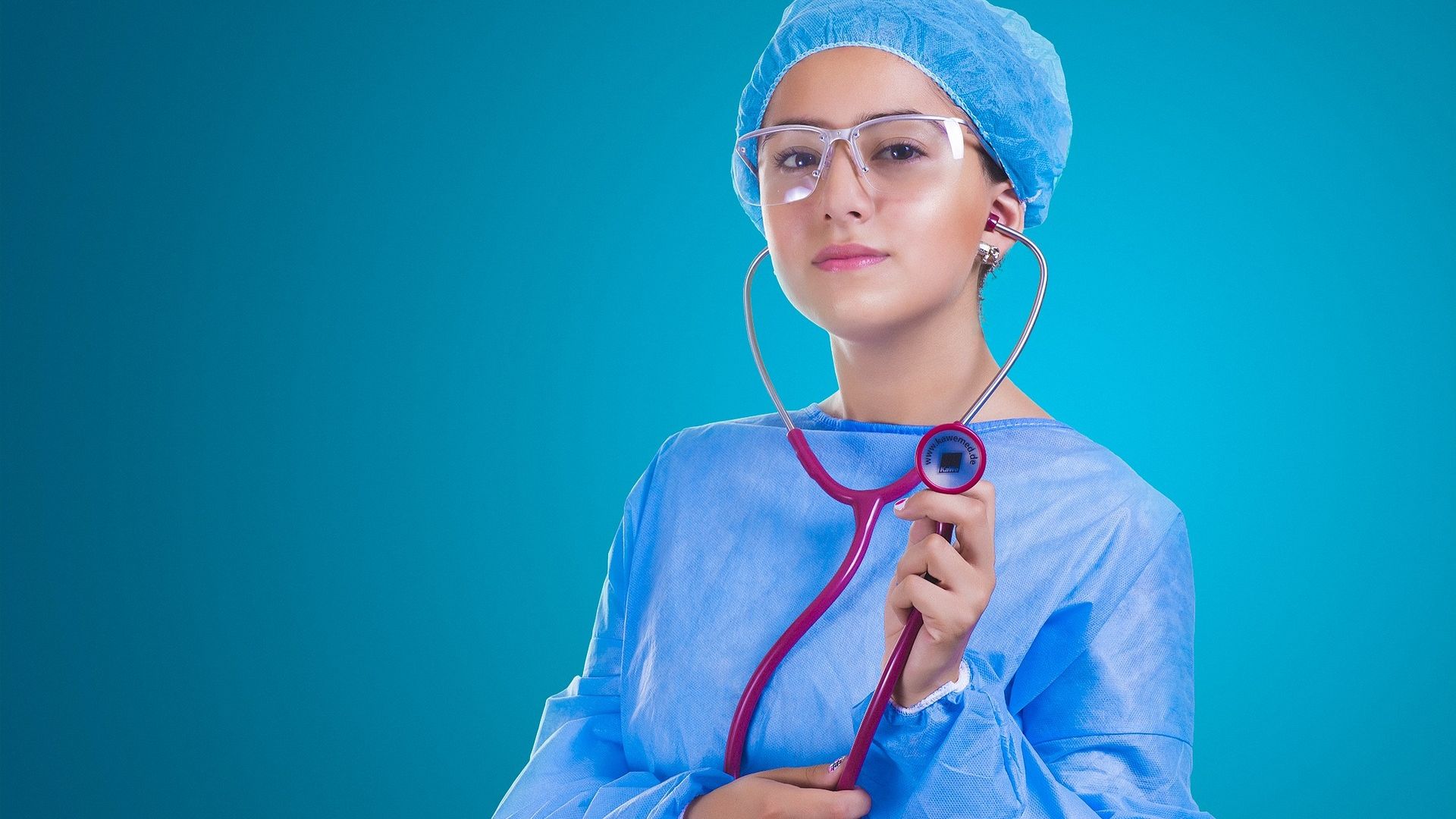 Woman in a medical gown and hat holding a stethoscope
